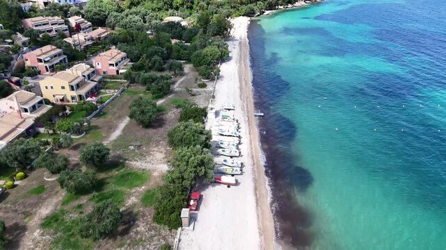 Idyllic summer day at Barbati Beach, Corfu. Crystal clear water rolling onto the pristine shore surrounded by green hills.