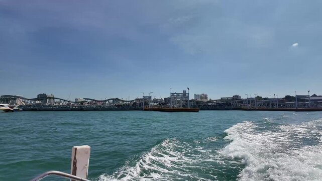Pattaya, Thailand - December 10, 2025: Wide harbor view of Bali Hai Pier and coastal cityscape from a moving boat, maritime tourism and transport infrastructure in Southeast Asia