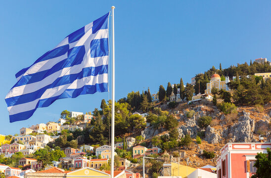 Greek Flag Above Colorful Hillside Houses on Symi Island in the Dodecanese Greece