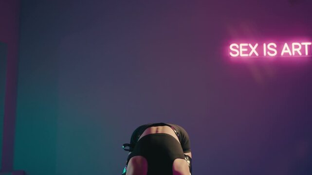 A young woman dances sensually in a dimly lit room with neon signs. She moves with confidence and rhythm, showcasing her body and artistic expression in a provocative way. vibrant atmosphere