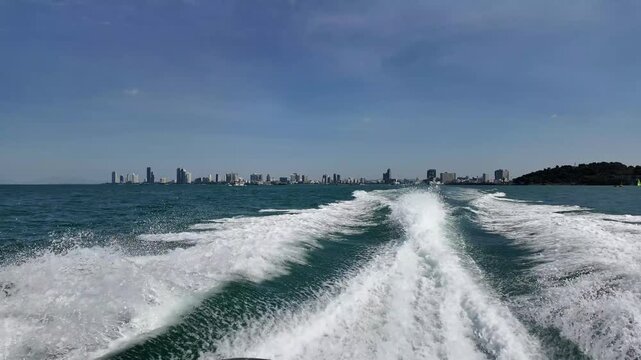 Pattaya skyline and boat wake from moving speedboat, maritime travel