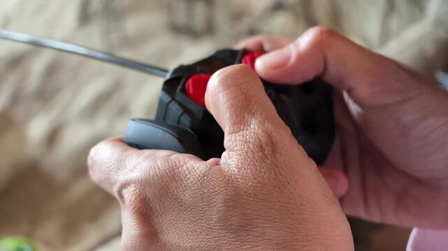 Slow motion side angle shot focusing on hands steering a black radio-control transmitter with red controls.
