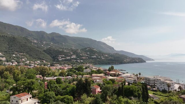 Aerial landscape of Ypsos beach and coastal road in Corfu, Greece. Crystal clear Ionian sea and mountain background.