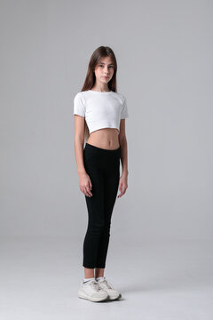 A teenage girl in a white crop top and black leggings poses in a photo studio, standing against a plain grey background from multiple angles