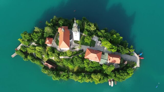 Top view footage of Bled Island and the Church of the Assumption surrounded by emerald waters of Lake Bled, Slovenia. Stunning summer landscape showcasing an iconic travel destination