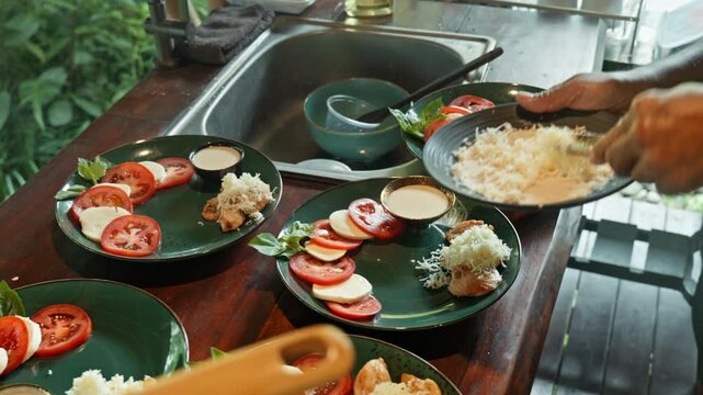 Caprese salad with ripe tomatoes, mozzarella cheese and fresh basil leaves on dark wooden boards. Close up with a chicken.