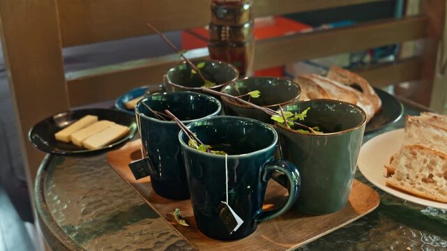 Hot herbal mint tea drink in mugs over wooden tray with fresh garden mint leaves,