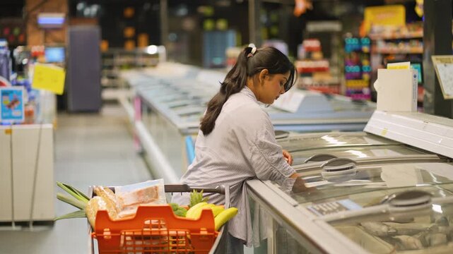 Indian woman buying frozen meat at the supermarket
