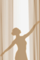 Silhouette, shadow on the wall of a graceful ballerina dancing behind curtains. © Lidiia Shapoval