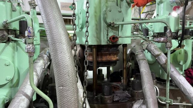 Ship main engine cylinder cover undergoing repair and inspection inside engine room compartment on commercial vessel for industrial maritime transport engineering service