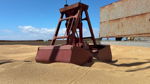 ship hatch full of grain crane grab lift.