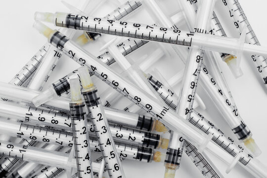 Scattered pile of empty medical syringes used in clinical and healthcare settings.