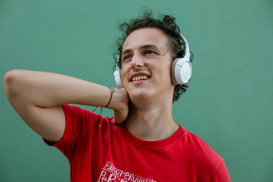 Young man listening to music. Relaxed young man listening to music and looking away with smile.