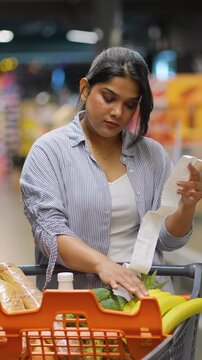 Concerned indian woman checking a long supermarket receipt