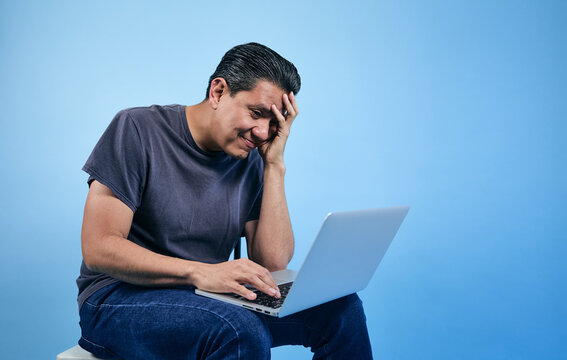 adult latino man using laptop on blue background in Mexico Latin America
