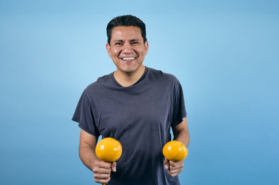 adult mexican man dancing and holding maracas on blue background in Mexico Latin America