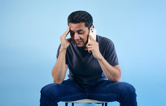 adult latino man talking in call and using phone on blue background in Mexico Latin America
