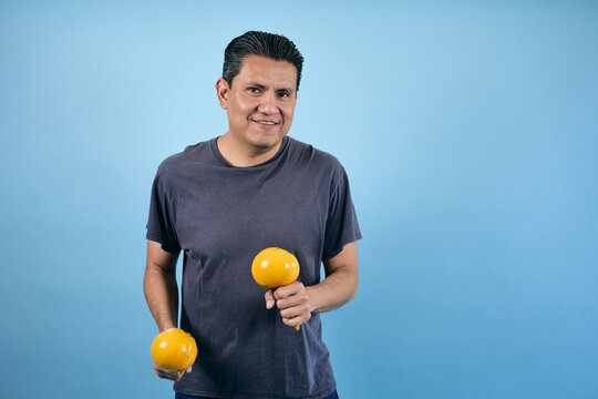 adult mexican man dancing and holding maracas on blue background in Mexico Latin America