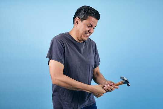 portrait of adult latin man holding a hammer in blue background in Mexico Latin America