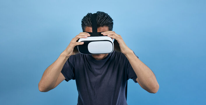 adult latin man using virtual reality glasses on blue background in Mexico Latin America, or mexican male portrait