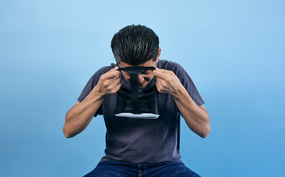 adult latin man using virtual reality glasses on blue background in Mexico Latin America, or mexican male portrait