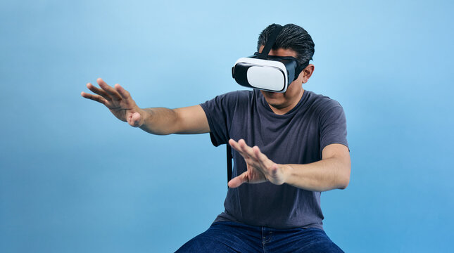 adult latin man using virtual reality glasses on blue background in Mexico Latin America, or mexican male portrait