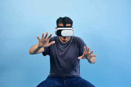 adult latin man using virtual reality glasses on blue background in Mexico Latin America, or mexican male portrait
