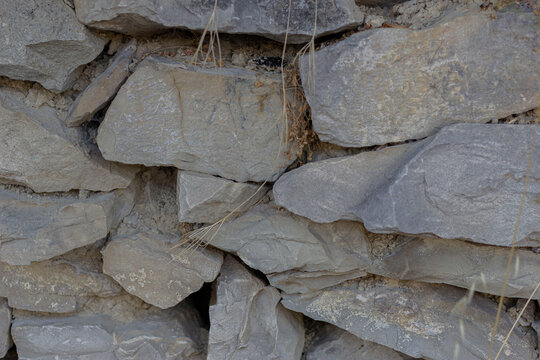 Traditional dry stone wall texture. Close up of stacked rough grey rocks. Natural masonry background with copy space