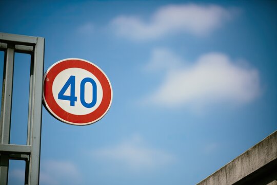 Circular road sign with "40" in blue against a bright sky