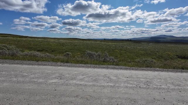 POV driving across Flatruet mountain plateau in Sweden. First-person view on a scenic gravel road through vast highland landscapes with mountains, tundra and open wilderness.