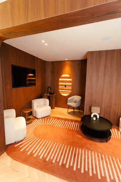 Minimalist waiting room with wood walls, armchairs, and lit shelves.
