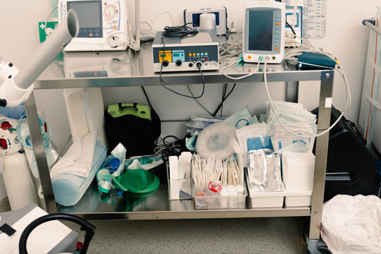 Steel cart holds electronic monitors above organized medical supplies.