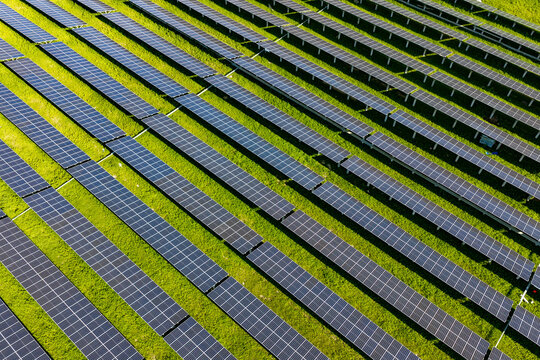 Geometric rows of solar panels on green grass