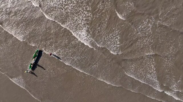 Still at Kapihak beach, a fishing boat returns with a large catch, swarmed by villagers&mdash;some helping to release the fish, others coming to buy the tembang fish