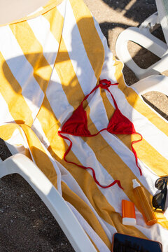 Red bikini top resting on a striped towel at the pool
