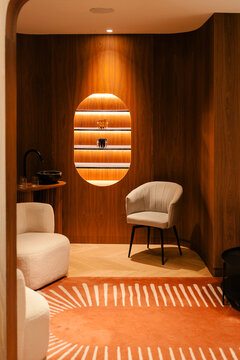 Sleek clinic with wood walls, lit shelf, beige seats, and a rug.