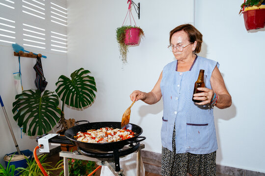 Senior woman cooking seafood paella outdoors for a meal
