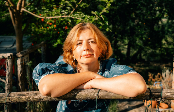 Woman Relaxing in Garden During Sunny Day With Trees in Background