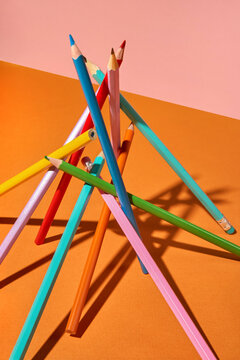 Colored Pencils Balanced in Abstract Arrangement on Orange Background