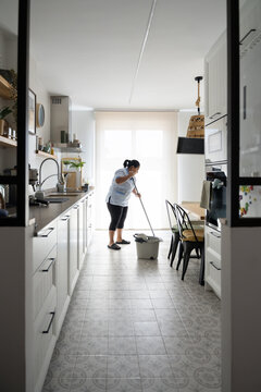 Housekeeper mopping kitchen floor in domestic service