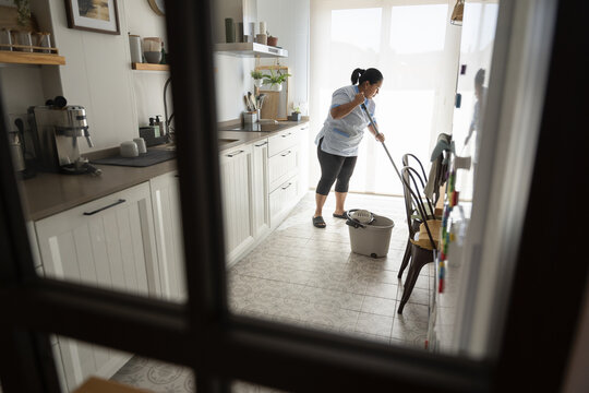 Housekeeper mopping kitchen floor for cleanliness