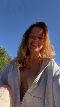 A woman laughs into the camera against a deep blue summer sky