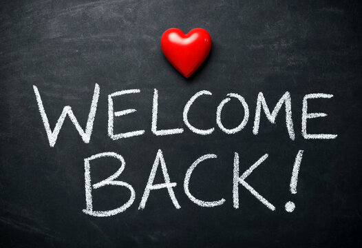 Chalkboard with welcome back message and red heart symbol written in white chalk