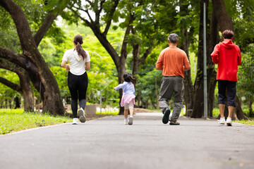 Fototapeta premium Backview Family exercising and jogging together in city park summer. healthy lifestyle in nature. Father mother, kids daughter exercise. Family team, children. healthy lifestyle and family bonding