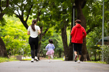 Obraz premium Backview Family exercising and jogging together in city park summer. healthy lifestyle in nature. Father mother, kids daughter exercise. Family team, children. healthy lifestyle and family bonding