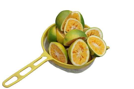 Una toma de cerca de varias naranjas cortadas dentro de un colador amarillo para hacer jugo de naranja en un fondo transparente 