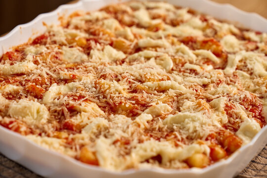 Gnocchi topped with tomato sauce, mozzarella and cheese in ceramic baking dish