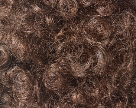 brown curly hair in full frame background, thick wavy strands and natural messy curls in close-up view, beauty and haircare concept