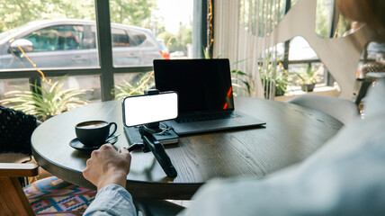 Obraz premium Person working remotely with laptop and phone on a cafe table with coffee