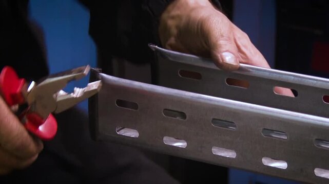 Worker using pliers to adjust metal bracket